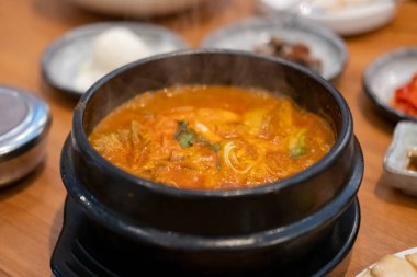 Kimchi Çorbası kasede servis edilir ve Kore mezeleri masada servis edilir.