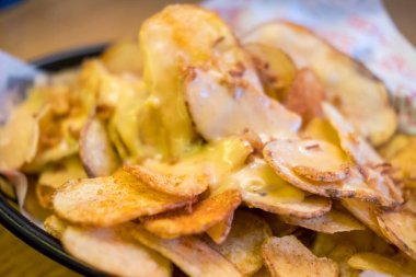 Üstünde peynir olan kızarmış cipsler, tabakta.