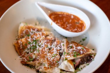 Üzerinde mozzarella peyniri bulunan füme domuz eti ve hardallı bbq sosuyla servis edilen roti quesadillas..