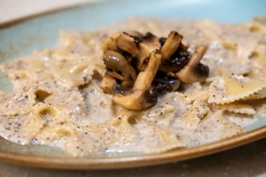 Farfalle mantarlı makarna tabakta servis edilir. Kelebek ya da papyon şeklinde bir makarna.