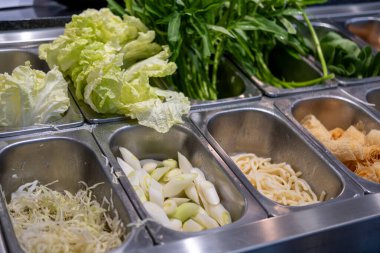 Restorandaki salata barında taze sebze seçimi, marul, doğranmış lahana, su ıspanağı ve daha fazlası da dahil.