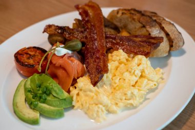 Çırpılmış yumurta, pastırma, somon ve ekmek tabakta servis edilir.