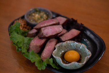 Yumurta sarısı ve sosla servis edilen ızgara sığır dili.