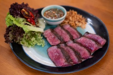 Orta pişmiş Picanha bifteği tabakta sebzeyle servis edilir.