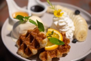 Vanilyalı gözleme, dilimlenmiş muz, krem şanti ve sos ile servis edilir..