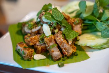 Baharatlı çıtır domuz salatası ya da Larb. Tayland yemeği, tabakta servis edilir..