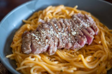 Carbonara soslu spagetti dilimlenmiş biftekle servis edilir.