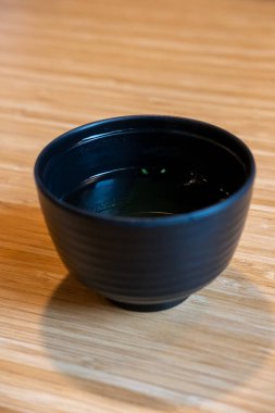 Siyah bardakta temiz çorba, Japon yemeği. Tahta masada.