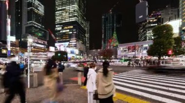 Tokyo, Japonya - 28 Kasım 2022: Araba trafiğinin zaman aşımı, kalabalık Shibuya geçidinde gece yürüyor. Turizm, Japonya turizmi, Asya taşımacılığı, Asya şehir hayatı kavramı