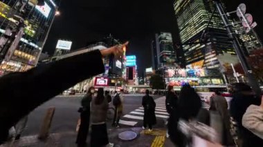 Tokyo, Japonya - 28 Kasım 2022: Araba trafiğinin zaman aşımı, kalabalık Shibuya geçidinde gece yürüyor. Turizm, Japonya turizmi, Asya taşımacılığı, Asya şehir hayatı kavramı