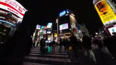 Tokyo, Japonya - 1 Aralık 2022: Araba trafiğinin zaman aşımı, kalabalık Shibuya geçidinde gece yürüyor. Turizm, Japonya turizmi, Asya taşımacılığı, Asya şehir hayatı kavramı