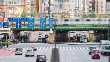 Tokyo, Japan - Dec 2, 2022: Time lapse of car traffic transportation on road, subway train, Japanese people walk cross junction in Shinjuku district, Tokyo Japan. Asia transport, Asian city life.