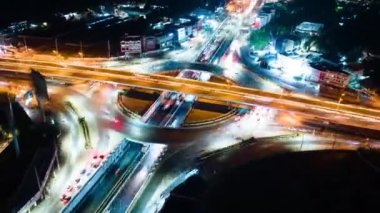 Hyperlapse time-lapse of car traffic transportation above circle roundabout road in urban downtown Asian city at night. Drone aerial view, high angle. Public transport or commuter city life concept