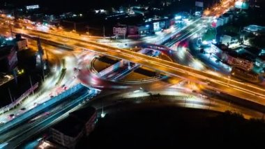 Hyperlapse time-lapse of car traffic transportation above circle roundabout road in urban downtown Asian city at night. Drone aerial view, high angle. Public transport or commuter city life concept