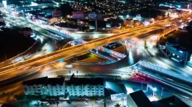 Hyperlapse time-lapse of car traffic transportation above circle roundabout road in urban downtown Asian city at night. Drone aerial view, high angle. Public transport or commuter city life concept