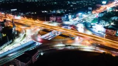 Hyperlapse time-lapse of car traffic transportation above circle roundabout road in urban downtown Asian city at night. Drone aerial view, high angle. Public transport or commuter city life concept