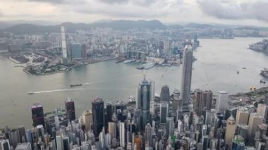 Hong Kong adasının şehir manzarası, İHA 'lı hava gününden geceye hiperhız zaman atlaması. Finans bölgesindeki gökdelen binaları, Victoria Limanı 'ndaki gemi ulaşımı. Asya turizmi şehir simgesi