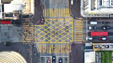 Araba trafiği yolda, yayalar zebra geçidini geçiyor, Mong Kok kavşağında, Hong Kong şehir merkezinde. İnsansız hava aracı üst görüntüsü. Asya yaşam tarzı, Asya ulaşım şehir yaşamı
