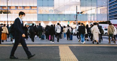 Tokyo, Japonya - 2 Aralık 2022: Japon iş adamlarından oluşan büyük bir kalabalık Shinjuku şehir merkezinde akşam saatlerinde banliyö yolunda yürüyor. Asya taşımacılığı, Asya toplumu, şehir hayatı