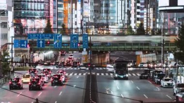 Tokyo, Japonya - 2 Aralık 2022: Metro treninin zaman aşımı, yoldaki araba trafiği, Japonlar Shinjuku 'da Zebra Geçidi' nden karşıya yürüyorlar. Asya banliyö ulaşımı, Asya şehir gece hayatı
