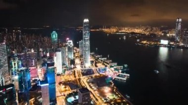 Hong Kong adasının şehir manzarası, insansız hava aracı gece hiperhız zaman atlaması. Finans bölgesindeki gökdelen binaları, Victoria Limanı 'ndaki gemi ulaşımı. Asya turizm seyahat kavramı