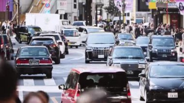 Tokyo, Japonya - 7 Ekim 2023: Asyalı kalabalığı yürüyor, Shibuya kavşağındaki yolda taksi trafiği var. Japon banliyö kültürü yaşam tarzı, turizm tarihi, Asya taşımacılığı, şehir hayatı