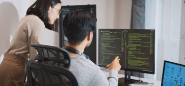 Genç yetişkin Asyalı erkek, kadın yazılım geliştirici masaüstü bilgisayarında kodlama programı. Erkek, kadın evden çalışıyor, uzaktan çalışıyor, serbest programcılık yapıyor, akıllı dijital göçebe yaşam tarzı kavramı.