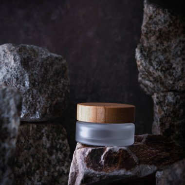 Background for cosmetic product branding, identity and packaging inspiration. Cosmetic bottle on dark stone podium with dark background.