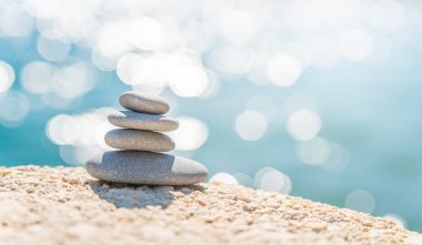 Mavi deniz arka planında güneşli bir günde deniz kıyısındaki piramit taşları. İyi tatiller. Çakıl taşı plajı, sakin deniz, seyahat yeri. Denizde mutlu tatil kavramı, meditasyon, spa, sakinlik..
