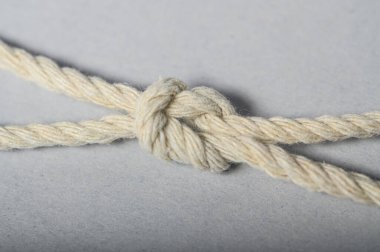 Tarafsız bir zemine karşı doğal halatla oluşturulmuş el yapımı bir düğüme ayrıntılı bir bakış.
