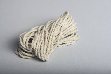 Sarılmış pamuk halat gri bir yüzeye yerleştirilir, çeşitli el sanatları ve ev kullanımı için uygundur..