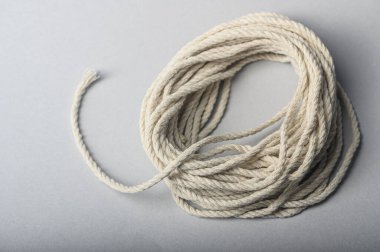 Pamuk ipin sarmalanmış bir uzunluğu gri bir yüzeyde, el yapımı veya bağlamada kullanılmaya hazırdır..
