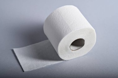 Yumuşak beyaz tuvalet kağıdı kağıdı düz bir yüzeyde oturur ve kalitesini ve dokusunu vurgular..