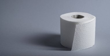 Taze beyaz tuvalet kağıdı gri bir yüzeye oturmuş, temizlik ve rahatlığı vurguluyor..