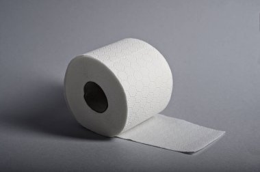 Gri arka plandaki yumuşak beyaz tuvalet kağıdı hijyen ve rahatlıktaki rolünü vurgular..