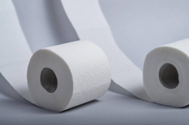 İki rulo yumuşak, beyaz tuvalet kâğıdı temiz bir banyo zemininde, hijyeni destekliyor..
