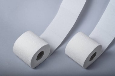 İki yumuşak beyaz tuvalet kağıdı sergileniyor, biri sarılı, tuvalet temizliğine uygun..