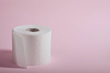 Bir rulo yumuşak beyaz tuvalet kağıdı. Hijyen kullanımı için pastel pembe bir zemin üzerine sergileniyor..