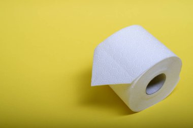 Parlak sarı yüzey üzerindeki beyaz tuvalet kağıdı tuvalet temizliğini ön plana çıkarıyor..