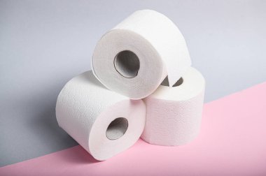 Üç rulo yumuşak beyaz tuvalet kağıdı. Hijyen için pastel arka planda istiflenmiş..
