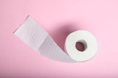 Yumuşak bir tuvalet kağıdı rulosu, tuvalet gereksinimleri için pembe bir zemine hafifçe açılıyor..