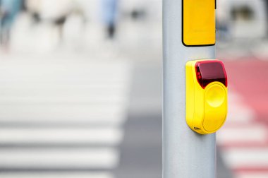 Parlak sarı bir yaya geçidi direğine monte edilir ve yayaları trafik durakları için sinyal vermeye davet eder..