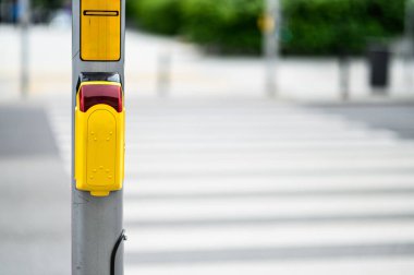 Yaya geçidine sarı bir yaya sinyal düğmesi monte edilir ve açık bir günde kalabalık bir şehir bölgesinden güvenli geçiş çağrısı yapılır..