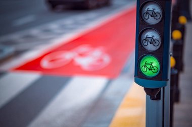 Bisikletler hareketli bir şehir kavşağında yeşil ışıkta, kaldırımda bisiklet yolu işaretli..