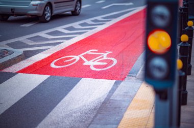 Yoğun bir kavşakta parlak boyalı bisiklet şeridi renk değiştiren bir trafik ışığı içerir. Öğleden sonra ışığı sahneyi güzelleştirir..