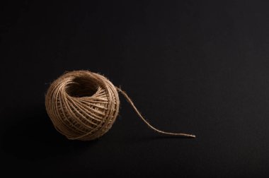 Basit bir doğal sicim topu karanlık bir yüzeye dayanır. Dokusunu ve şeklini minimalist bir düzende gösterir..