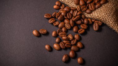 Kavrulmuş kahve çekirdekleri çuvala düşer ve mutfaktaki koyu bir tezgahta davetkar bir atmosfer yaratır..