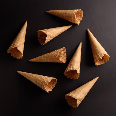 Waffle külahları koyu bir yüzeyde, taze dokularını sergiliyorlar ve dondurmayla doldurulmaya hazırlar..