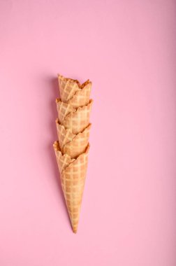 Dört çıtır waffle külahı, ılık bir yaz günü dondurma servis etmek için mükemmel yumuşak pembe bir arka fona güzelce istiflenir..