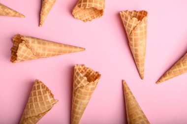 Değişik oryantasyonların gözleme külahları yumuşak pembe bir zemin üzerinde uzanır ve onları lezzetle dolduracak mükemmel dondurma kepçesini beklerler..